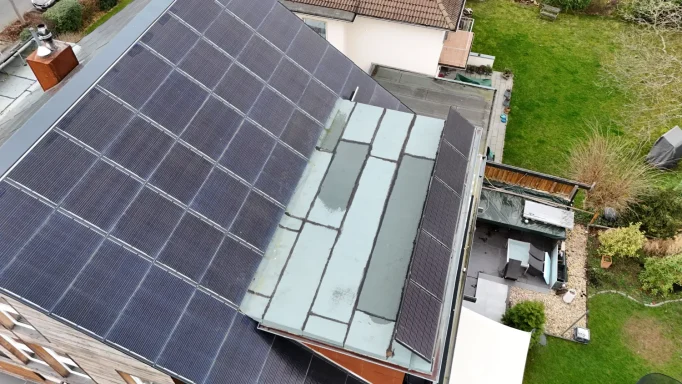Dach mit Solarpaneelen und moderne Glas-Elemente in ruhiger Gartenlandschaft.